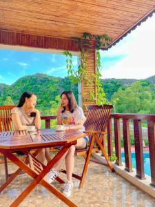 宁平Trang An Resort的坐在一张桌子旁的两位妇女用手机说话