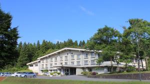 鹤冈市Kyukamura Shonai-Haguro的大型酒店,停车场内有车辆停放