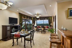 日惹Sahid Raya Hotel & Convention Yogyakarta的客厅配有桌椅和电视。