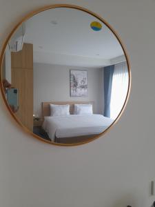 芽庄Happy Home的一间卧室配有床和圆镜子