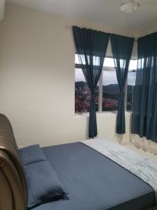 Bandar Puncak AlamYuslina Homestay的一间卧室配有一张带蓝色窗帘的床和一扇窗户