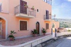 库斯托纳奇Appartamento Custonaci Uno的前面有盆栽植物的粉红色房子