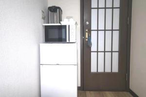 东京Kiki HouseH --Self Check-in -- Room Number & Password is in the following email的门边冰箱上的一个微波炉