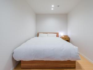ItoshimaRakuten STAY HOUSE x WILL STYLE Itoshima 102的一间卧室配有一张带白色床单的大床