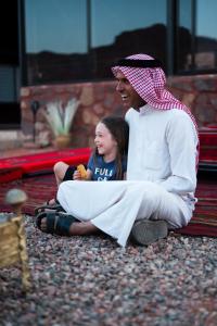 瓦迪拉姆Milky Way Bedouin Camp的坐在地上的男人和一个小女孩