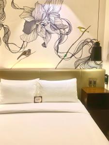 巴科洛德The Henry Hotel Roost Bacolod的卧室配有一张挂有花卉画的床铺。