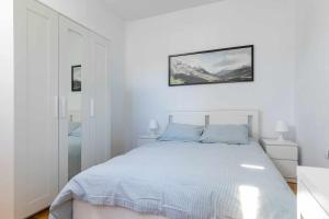 马德里Confortable piso 3 habitaciones en Retiro Atocha的白色的卧室配有一张床,墙上挂着一幅画