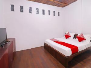 占碑市OYO 91807 Kemalasari Guesthouse的一间卧室配有一张床和一台平面电视
