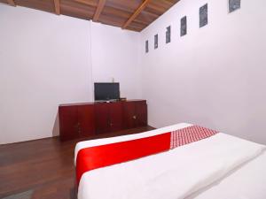 占碑市OYO 91807 Kemalasari Guesthouse的一间卧室设有红色和白色的床和一台电视。