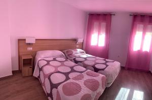 塔韦尔纳斯ALOJAMIENTOS AGAVE的卧室内的两张床和粉红色窗帘
