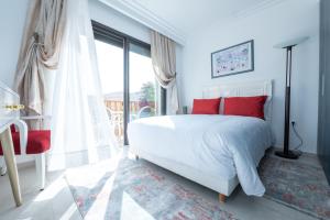 阿加迪尔Villa Palmeraie Golf Agadir的卧室配有白色的床、红色枕头和窗户