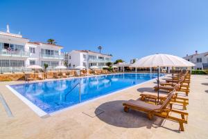 萨尔加Naranjos Resort Menorca的一个带躺椅和遮阳伞的游泳池