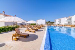 萨尔加Naranjos Resort Menorca的游泳池旁的一排椅子和遮阳伞
