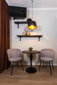 杰尔Apáca 30 Apartman **** Győr的一间设有两把椅子、一张桌子和一台电视的房间