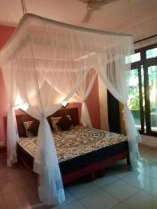 阿鲁特伽马Villa Bentota River View的卧室配有带白色窗帘的天蓬床