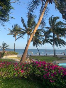 马林迪Kaleb's Beachfront Villa的享有海滩、棕榈树和鲜花的景致。