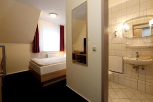 卡门Hotel Stadt Kamen的浴室设有床、水槽和镜子
