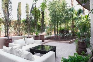 马拉喀什洛尔宫Spa酒店的庭院设有白色的沙发、桌子和树木