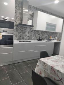 阿莫拉Lisbon, 3 bedroom apartment in Amora , 15 min from the beach的厨房配有白色橱柜和带桌布的桌子。