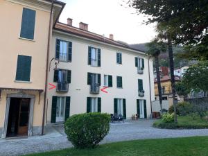 梅纳焦Villa Paola - Holiday Apartment - Menaggio, Lago di Como的白色的建筑,上面有黑色百叶窗