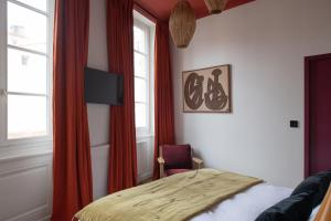 里昂MiHotel Blandan的一间卧室配有一张带红色窗帘的床和一把椅子
