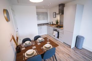 曼彻斯特The Interchange - 2-Beds - Brand New - Central的厨房以及带木桌和椅子的用餐室。
