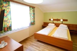 克查赫Pension Seiwald in Kötschach的一间卧室设有两张床、一张桌子和一个窗口