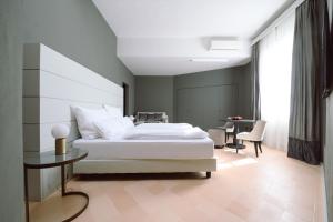 卢卡Palazzo Froussard B&B and Living的卧室配有一张白色的大床和一张桌子