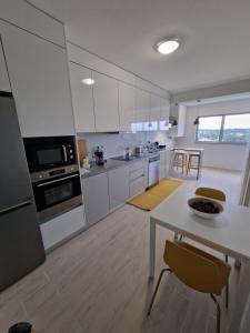 奥利韦拉-杜拜鲁Piso Panorama的厨房配有白色橱柜和桌椅