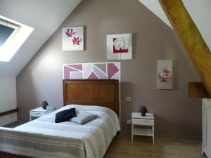 RentyLe gîte de l'AA的一间卧室配有一张床,墙上挂着一些绘画作品