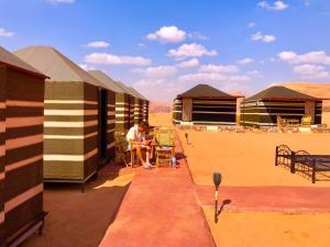 瓦迪拉姆Bedouin Tours Camp的坐在大楼外桌子上的男人