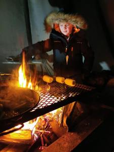 基律纳玛塔拉卡北极光旅舍的火炉旁的烤架上做饭的人
