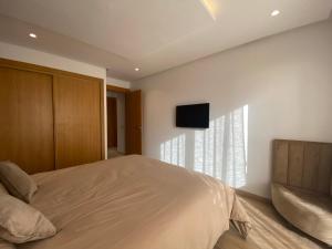卡萨布兰卡CORNICHE CASABLANCA - SUBLIME F2 NEUF的卧室配有一张床,墙上配有电视