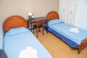 亚瓜龙hotel py jaguarão的客房设有两张床、一张桌子和一张桌子
