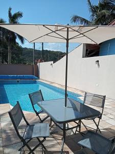 瓜鲁雅Refúgio BEM-TE-VI的游泳池旁配有遮阳伞的桌椅