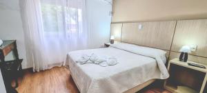 亚瓜龙hotel py jaguarão的一间卧室配有一张带白色床单的床和一扇窗户。
