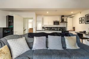 伯明翰Cosy Brand new spacious 1 bed luxury apartment的一间带灰色沙发的客厅和一间厨房