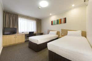 堪培拉Ramada Encore Belconnen的酒店客房设有两张床和一台平面电视。
