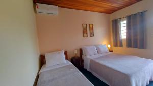 戈亚斯州上帕莱索Chalés Flor de Manacá的酒店客房设有两张床和窗户。