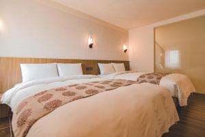 花莲市东城商旅的配有白色床单的酒店客房内的两张床