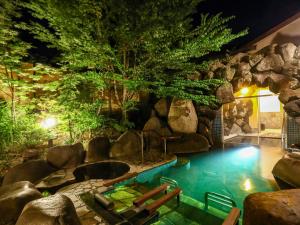 松本Keiryuso Siorie的一座位于度假村中心且带岩石墙的游泳池