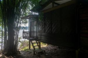Ban KhonPomelo Restaurant and Guesthouse's Fishermen Bungalow & A Tammarine Bungalow River Front的木舱,树旁设有长凳