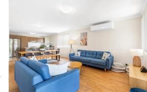 塞斯诺克Hunter Home with POOL / CINEMA ROOM / PING PONG的一间带2张蓝色沙发的客厅和一间厨房