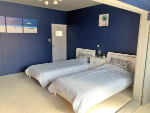 下田Ramjet Sotoura Beach House Shimoda的卧室设有两张床铺和蓝色的墙壁