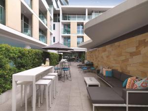 悉尼悉尼邦迪海滩阿迪娜公寓式酒店的一座配有白色桌椅的庭院和一座建筑