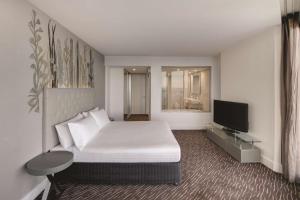 珀斯珀斯斯卡伯勒汇合酒店的卧室配有白色的床和平面电视。