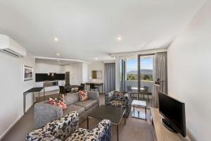堪培拉Adina Serviced Apartments Canberra Dickson的客厅配有沙发、椅子和电视