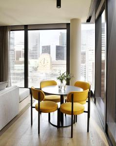 悉尼A by Adina Sydney的一间带桌椅和大窗户的用餐室