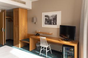 库雷萨雷乔治奥特斯温泉酒店的一间卧室配有一张桌子、一台电视和一把椅子