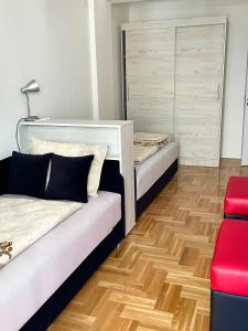 尼什City Apartmani Niš的一间设有两张床和红色椅子的房间